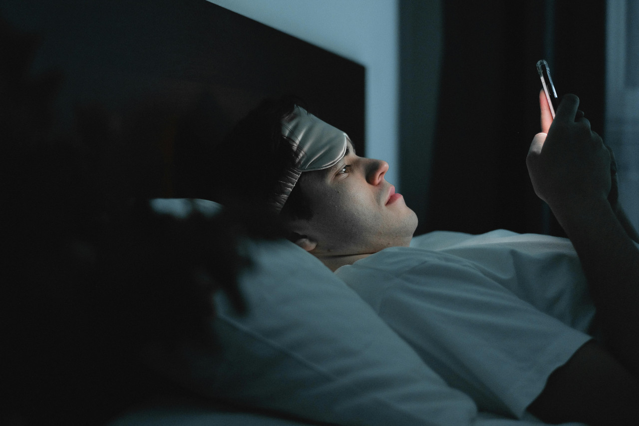 Celular en la cama. Fuente: Pexels.